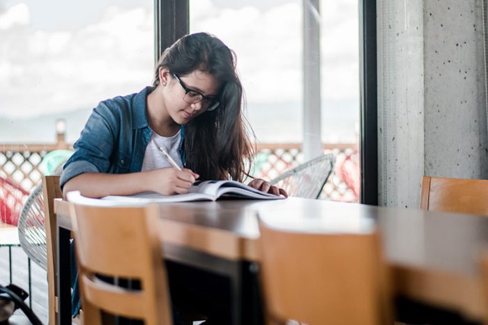 girl writing at kitchen table