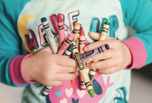 Child holding handful of crayons